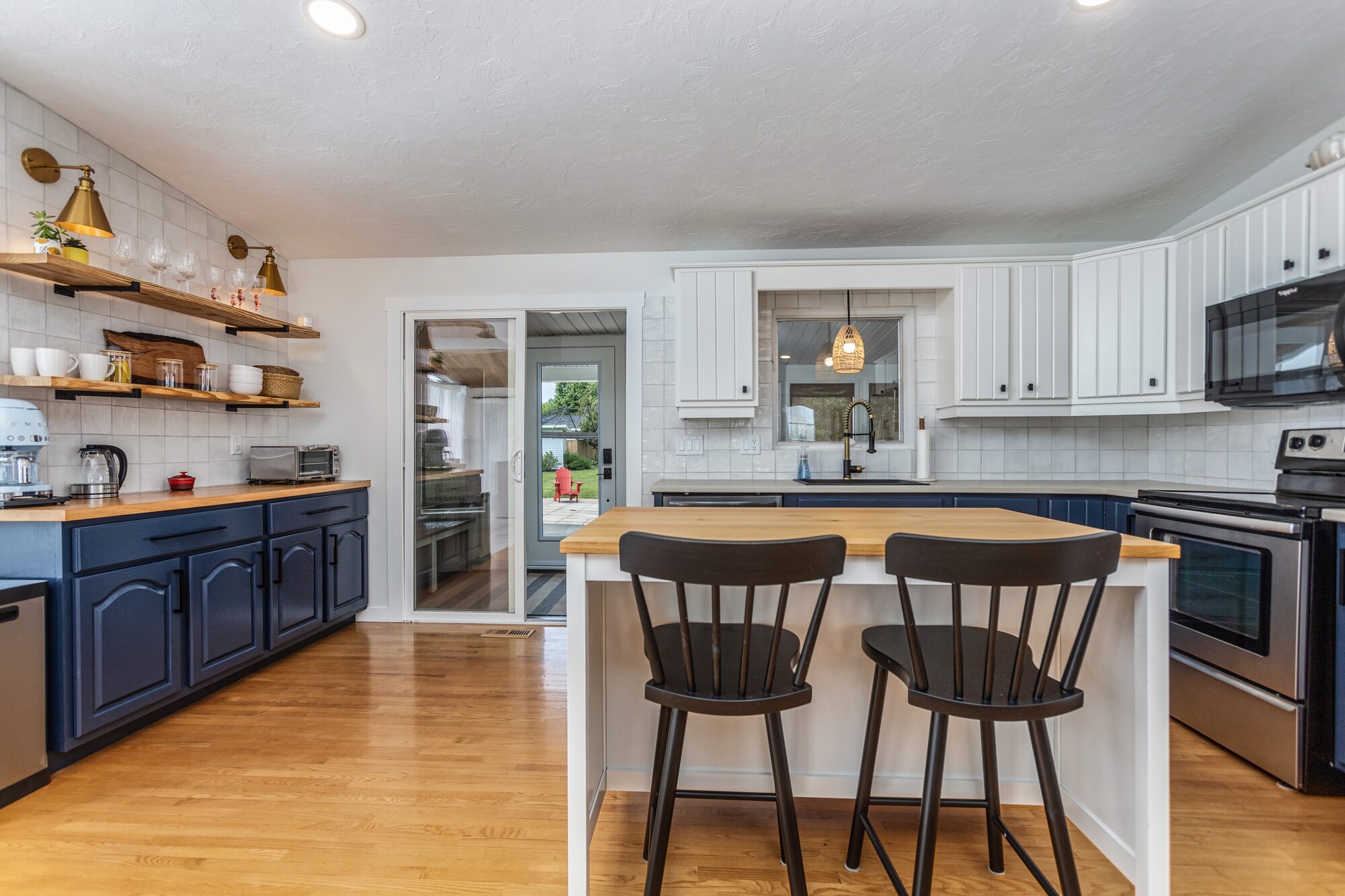 The kitchen, with butcher-block island, navy cabinetry, and brass sconces.
