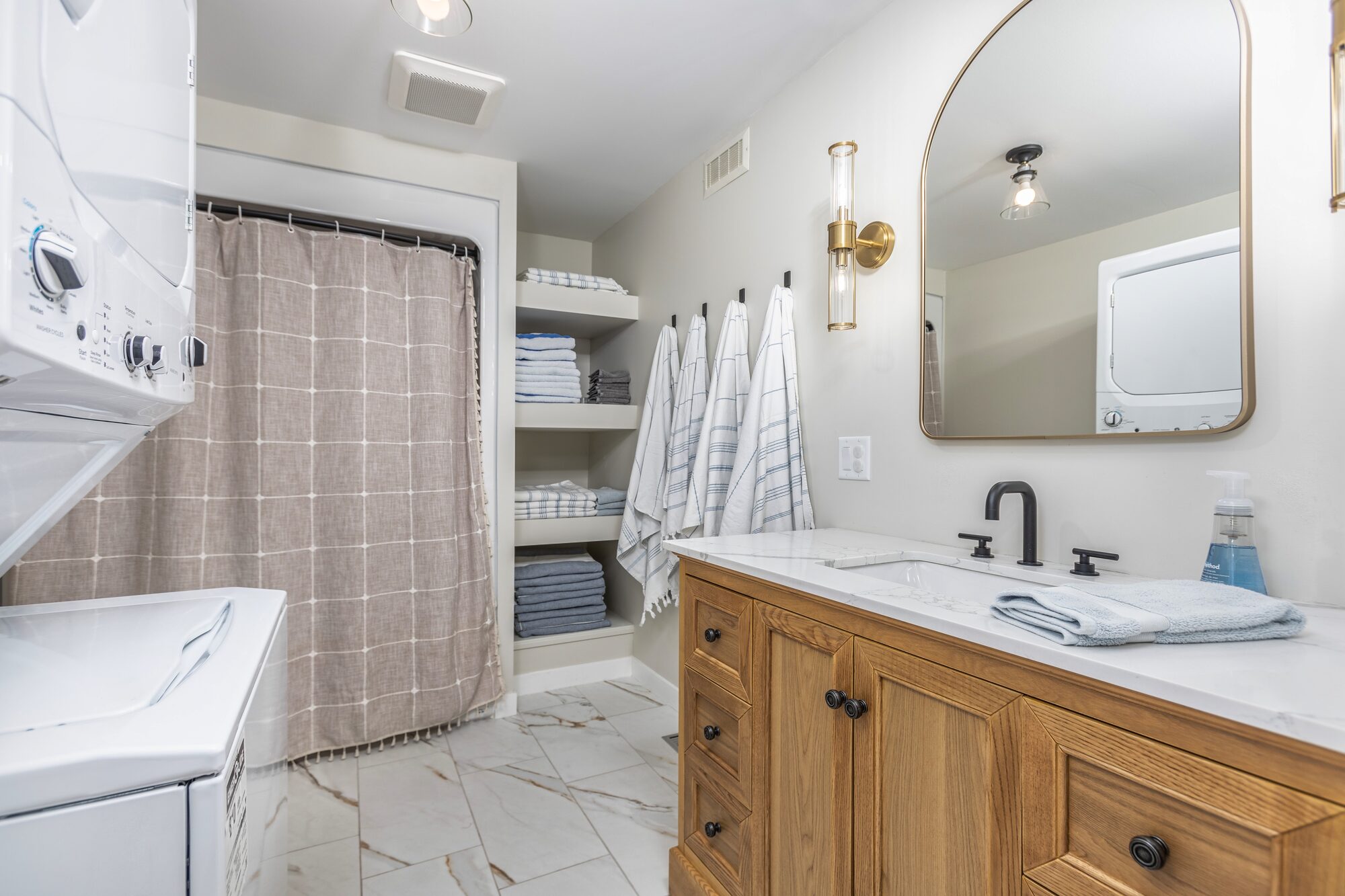 The downstairs full bath with washer and dryer, large mirror, marble vanity, and Turkish towels.