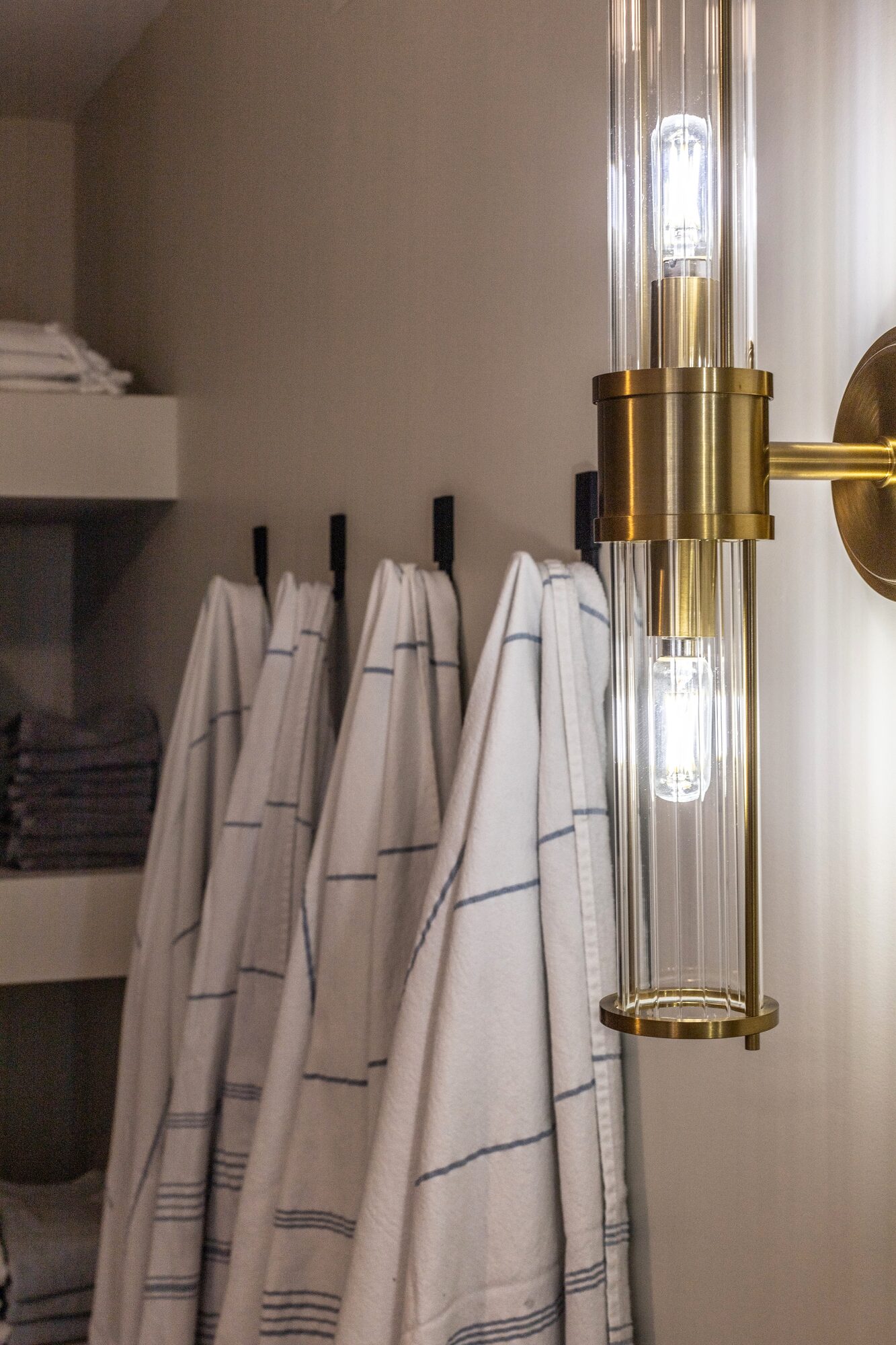 Detail: a brass-and-glass wall sconce above stacked Turkish towels.